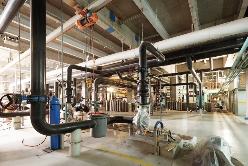 Commercial plumber Mobile AL working on industrial plumbing system with large pipes and equipment - professional plumbing services in Mobile Alabama