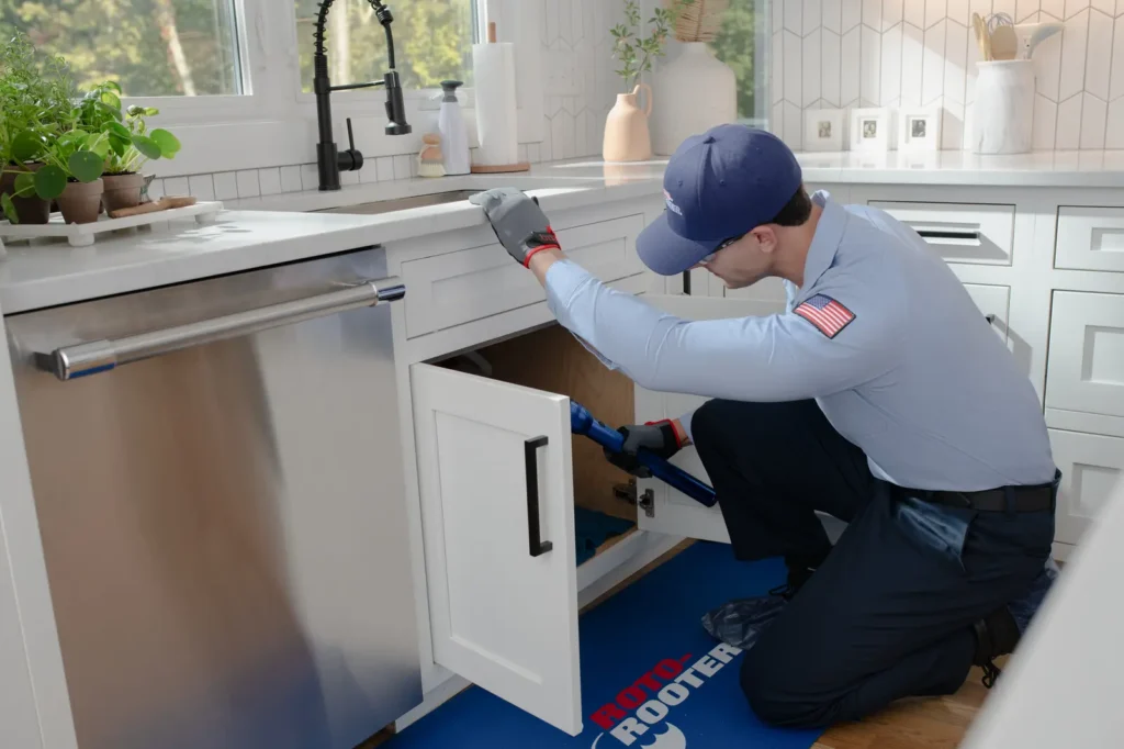 Residential plumber in Mobile AL repairing kitchen sink plumbing - Roto-Rooter technician providing professional home plumbing services in Baldwin County