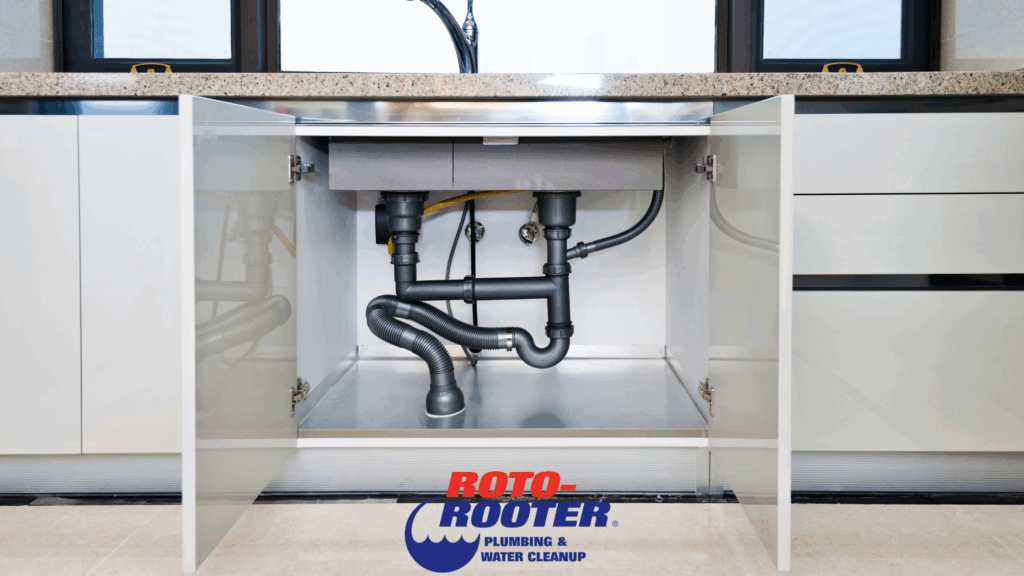 Open under-sink cabinet showing plumbing pipes, a common place where mold can grow in your plumbing system.
