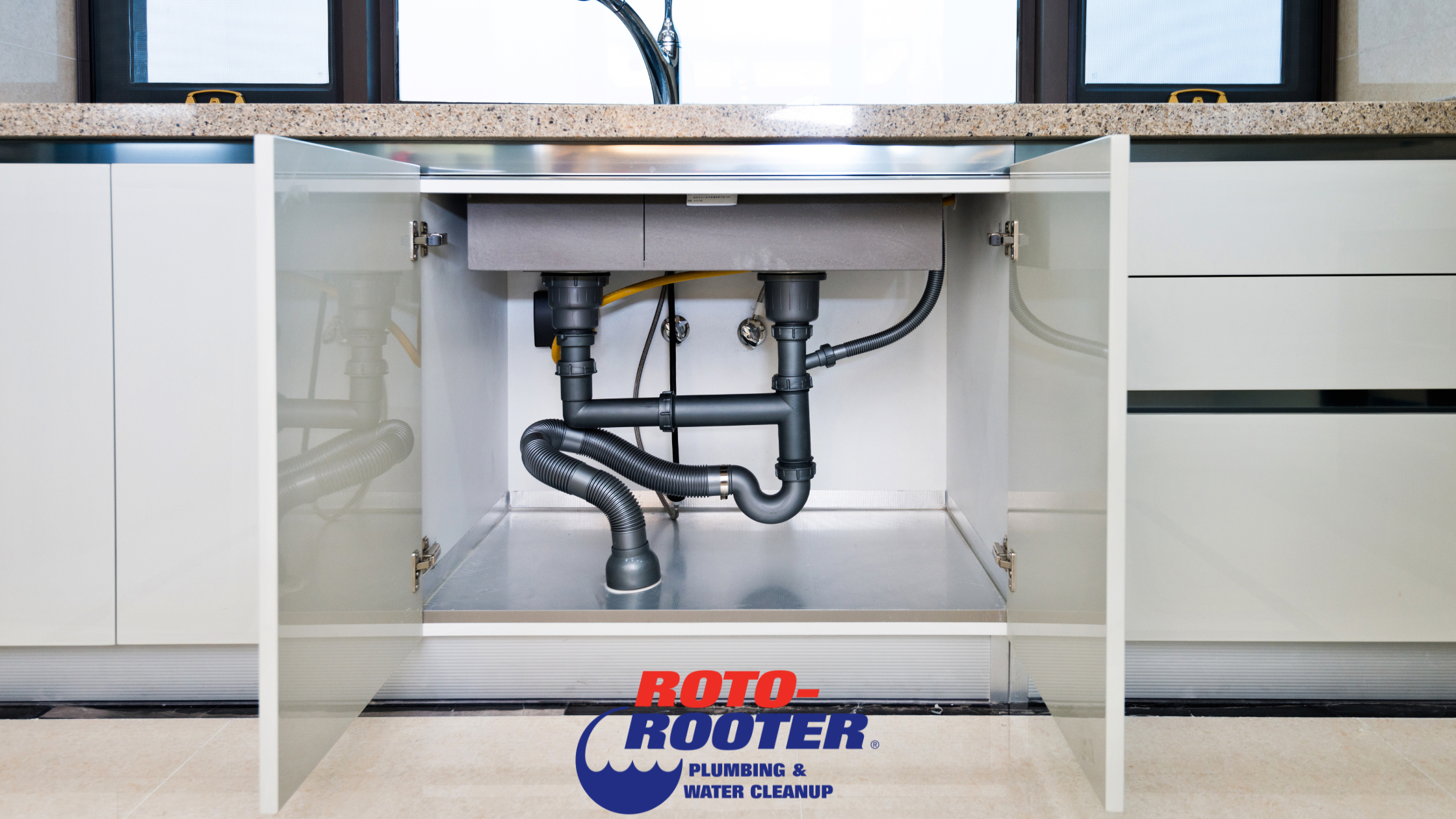 Open under-sink cabinet showing plumbing pipes, a common place where mold can grow in your plumbing system.