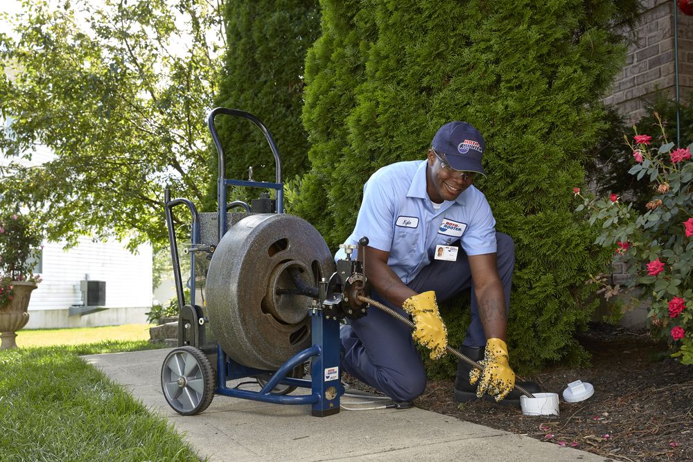 Roto-Rooter plumber clearing a main drain line at an outdoor cleanout